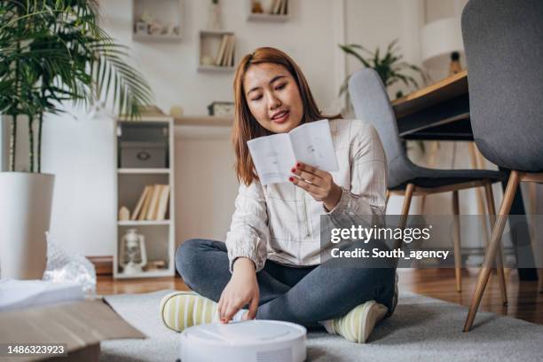 frau hat neuen roboter-staubsauger - bedienungsanleitung stock-fotos und bilder