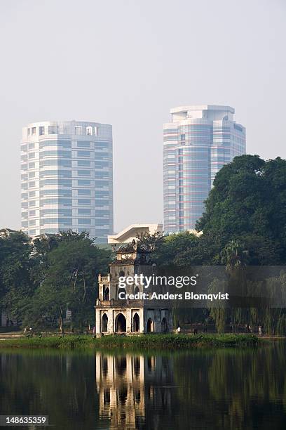 thap rua or tortoise tower in hoan kiem lake with modern skyscrapers in background. - hoan kiem lake photos et images de collection