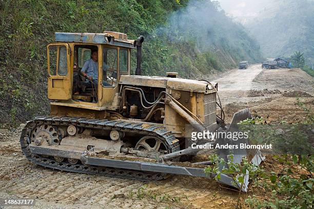 caterpillar working on roadbuilding project on road between meo vac and bao lac. - bao lac stock pictures, royalty-free photos & images