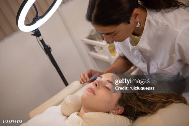 young woman during eyebrow lamination procedure - brow lamination stock pictures, royalty-free photos & images