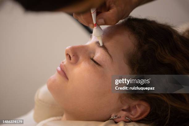 young woman during eyebrow lamination procedure - brow lamination stock pictures, royalty-free photos & images