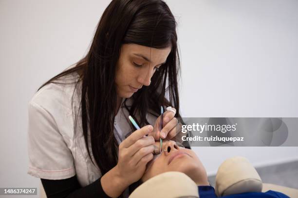 woman during eyelash extension procedure - eyebrow tweezers imagens e fotografias de stock