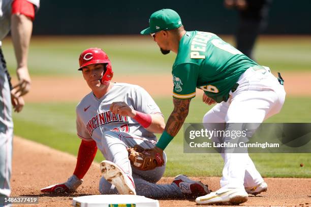 Tyler Stephenson of the Cincinnati Reds is tagged out at third base by Jace Peterson of the Oakland Athletics on a throw by Ramon Laureano of the...