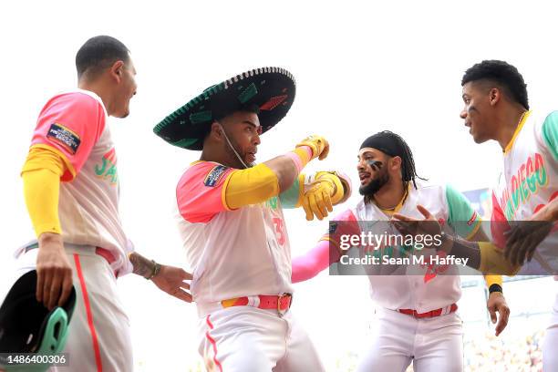 Fernando Tatis Jr. #23, Manny Machado, and Juan Soto congratulate Nelson Cruz of the San Diego Padres after his solo homerun during the third inning...