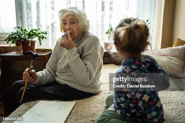 la bisabuela juega con la nieta, finge ponerse lápiz labial. - great grandmother fotografías e imágenes de stock