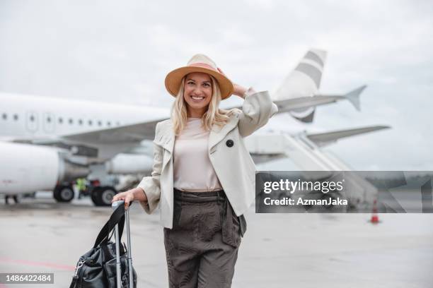 smiling female tourist in front of a plane - airport slovenia stockfoto's en -beelden