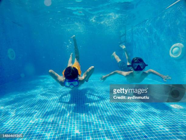teenager-kinder, die im schwimmbad unter wasser schwimmen - boy swimming stock-fotos und bilder