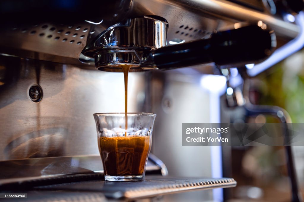 Espresso drops dripping from portafilter in small coffee shop