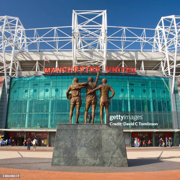 east facade of the manchester united football stadium, with statue of legends george best, denis law and bobby charlton, old trafford. - manchester united old trafford stadium stock pictures, royalty-free photos & images