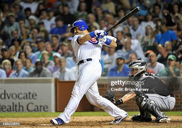 Geovany Soto of the Chicago Cubs follows through on an RBI single scoring teammate Alfonso Soriano as Brett Hayes of the Miami Marlins catches during...