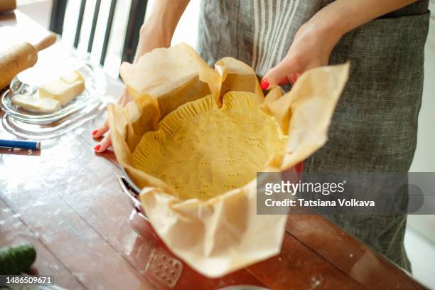 hands of white housewife holding red round pie can with parchment paper and pie crust - butter tart stock pictures, royalty-free photos & images