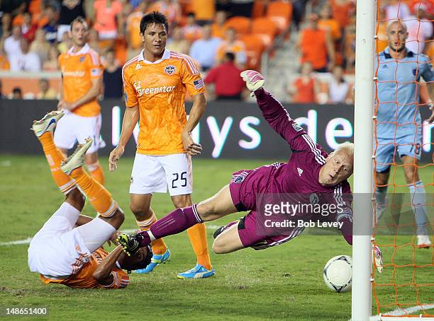 Calen Carr of the Houston Dynamo slips one past goalkeeper Jimmy Nielsen of the Sporting KC for a goal as Brian Ching of the Houston Dynamo looks on...