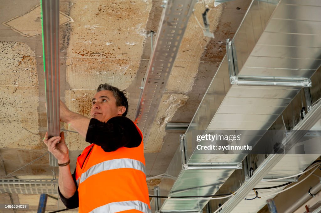 Trabajador de la construcción agarrando el marco de metal para montar un techo suspendido.