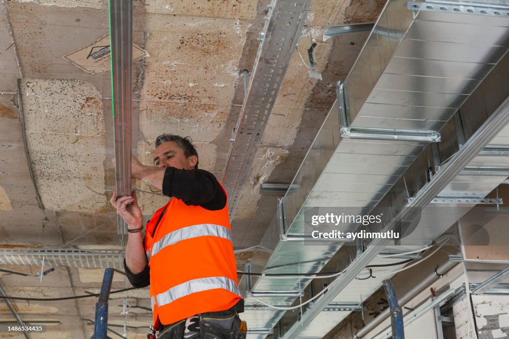 Construction worker grabbing the metal frame to assemble a suspended ceiling.