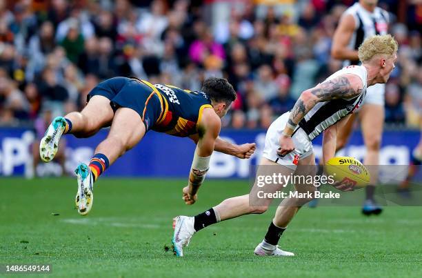 John Noble of the Magpies looks to handball under pressure from Chayce Jones of the Crows during the round seven AFL match between Adelaide Crows and...