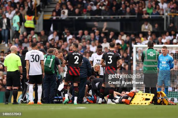 Andreas Pereira of Fulham receives medical treatment as he is surrounded by players during the Premier League match between Fulham FC and Manchester...