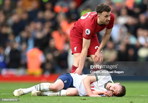 Diogo Jota of Liverpool with Oliver Skipp of Tottenham Hotspur after he goes down with an injury during the Premier League match between Liverpool FC...