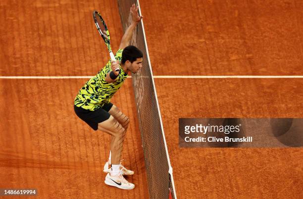 Carlos Alcaraz of Spain tries to avoid touching the net after sliding in to play a forehand volley against Grigor Dimitrov of Bulgaria during their...