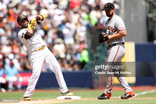 Nelson Cruz of the San Diego Padres reacts after hitting a triple as J.D. Davis of the San Francisco Giants looks on during the second inning of game...