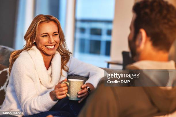 la pareja se relaja, la mujer feliz con café y el hombre tienen una conversación divertida, pasando tiempo de calidad en casa. amor, cuidado y confianza con las personas riendo juntas con comunicación, bebida latte y felicidad - kins fotografías e imágenes de stock