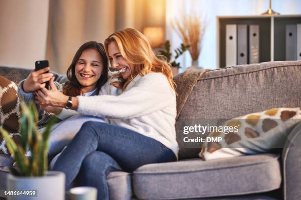 selfie, sorriso e mamma con adolescente sul divano, social media e legame felice con tempo di qualità per rilassarsi in salotto. immagine del profilo, madre e figlia sul divano insieme alla felicità in casa. - happy smile with phone foto e immagini stock