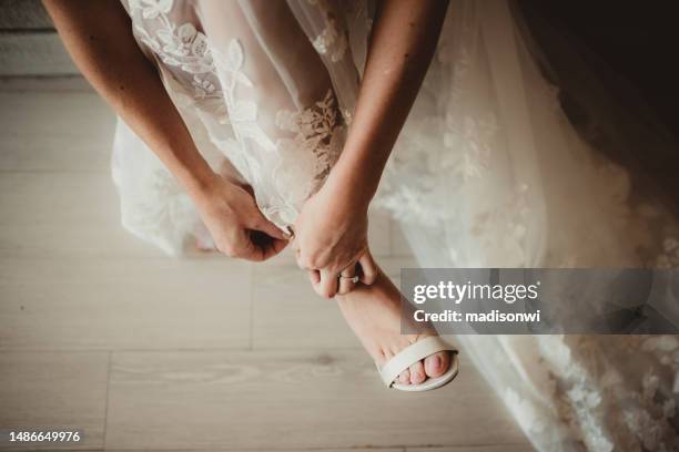 braut zieht ihre schuhe in ihrem hochzeitskleid an - wedding feet stock-fotos und bilder