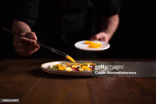 nahaufnahme eines männlichen kochs im restaurant, der einen teller carpaccio mit aprikosen dekoriert - carpaccio stock-fotos und bilder