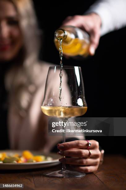 waiter serving white wine to a beautiful woman - italian food and wine stock pictures, royalty-free photos & images