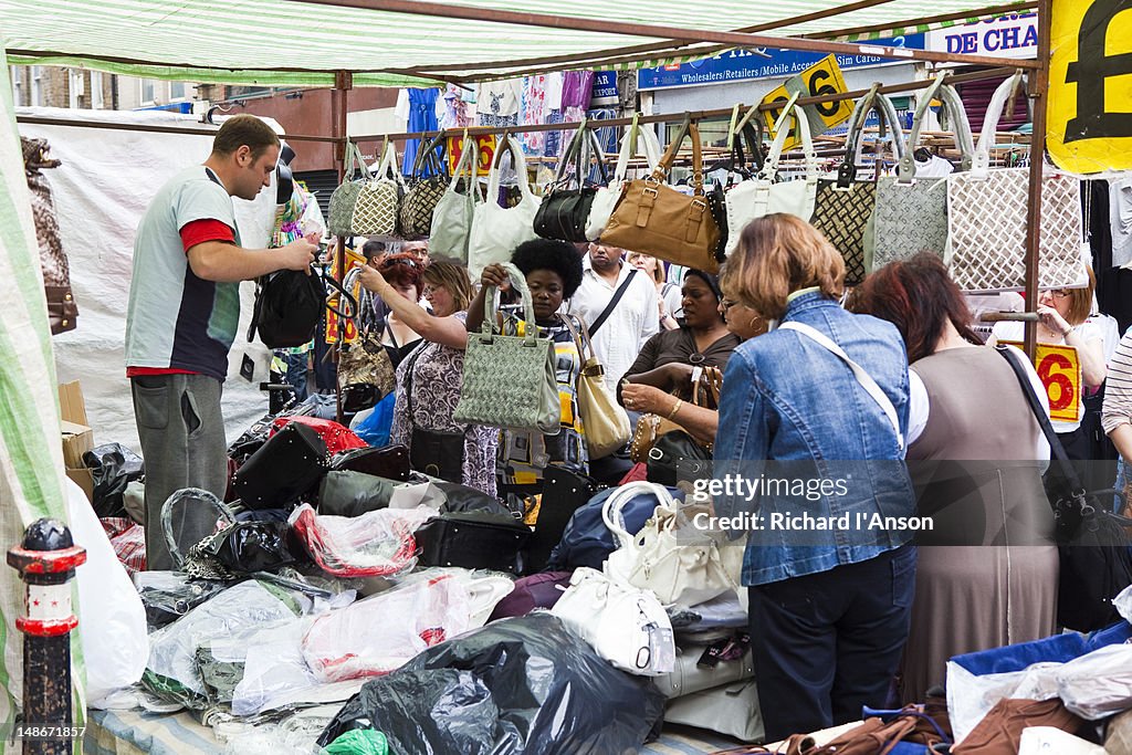Women shopping for handbags at Petticoat Lane market.