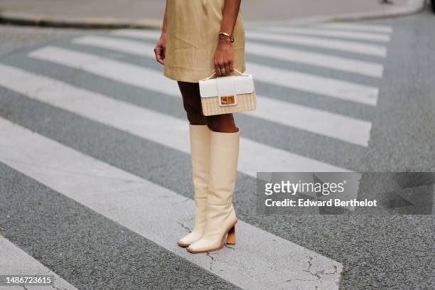 Emilie Joseph wears a pale yellow high neck / sleeveless / short dress, a camel shiny leather small belt, a beige wicker and white shiny leather...