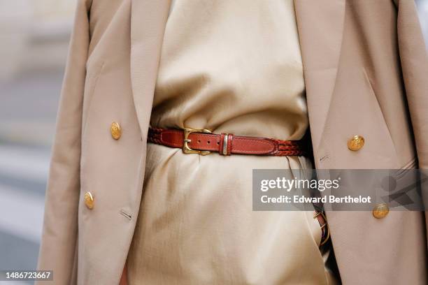 Emilie Joseph wears a pale yellow high neck / sleeveless / short dress, a camel shiny leather small belt, a beige with gold buttons blazer jacket,...