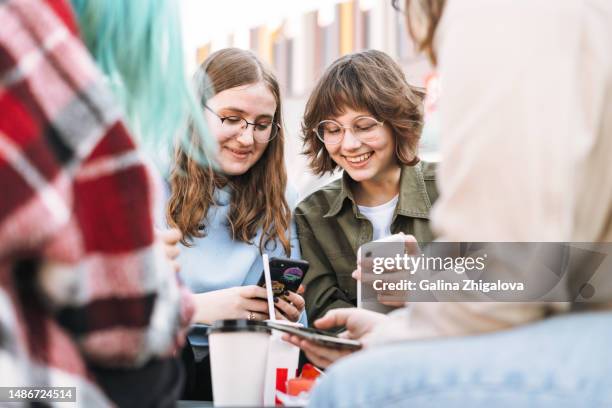 group of teenage girls laughing using mobile phone on street at city - child facebook stockfoto's en -beelden