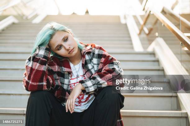 portrait of thinking teenage girl with blue hair sitting on stairs - girl with blue hair stock pictures, royalty-free photos & images