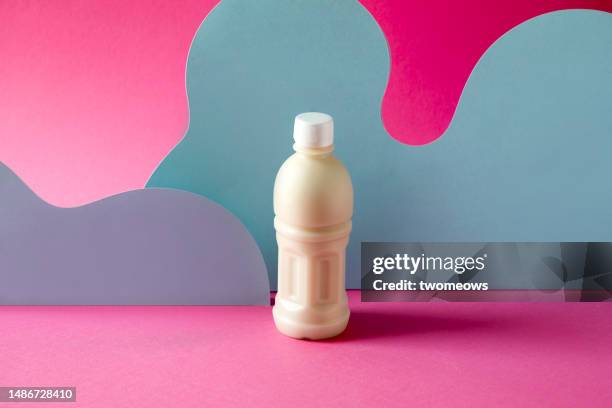 one opaque plastic bottle with milk on coloured background. - sojamilch stock-fotos und bilder