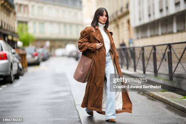 Heart Evangelista wears a white fluffy turtleneck / asymmetric cropped / backless pullover, a pale brown shiny leather oversized long jacket, a dark...