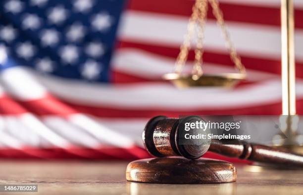 gavel and scales with a us flag in the background as symbols of a jurisdiction. - procedimento giudiziario foto e immagini stock
