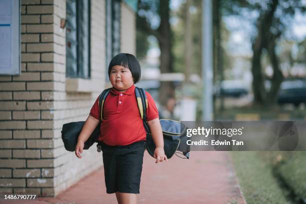 asian chinese young boy walking to golf driving range with golf bag for lesson practising - golf excitement stock pictures, royalty-free photos & images