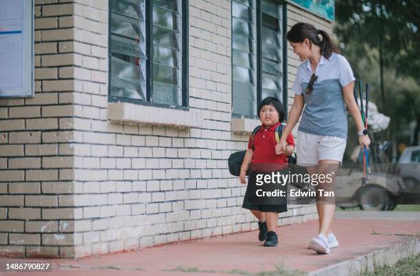 asian chinese female coach walking with small boy student holding hands toward driving range for golf lesson - golf bag stock pictures, royalty-free photos & images