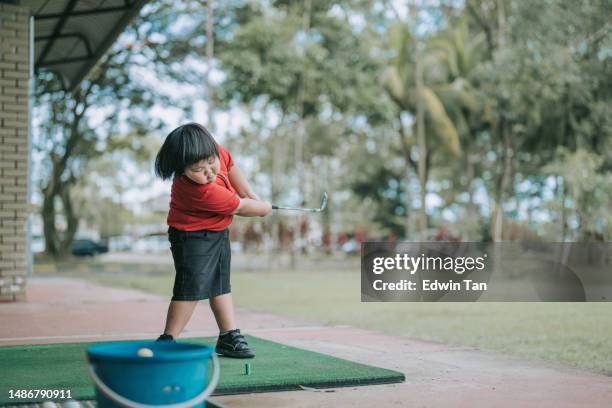 asiatischer chinesischer süßer junge, der während des golfkurses in der driving range goldschwung übt - golf swing stock-fotos und bilder