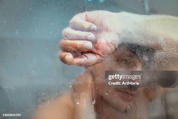 hombre cansado y triste tomando una ducha - hombre en la ducha fotografías e imágenes de stock