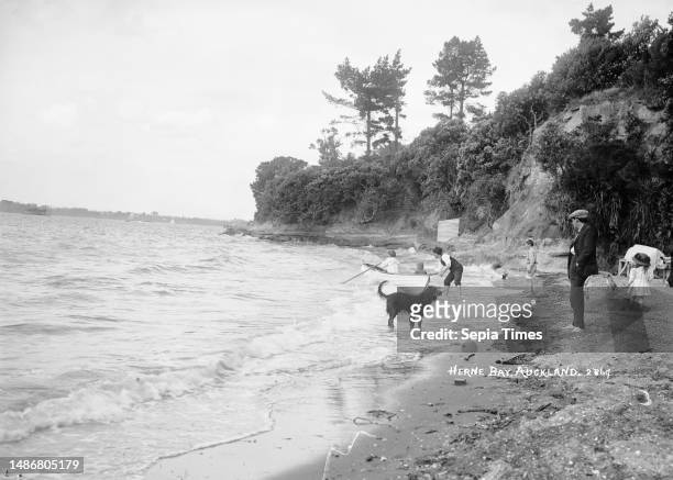 Rowboat at Herne Bay, Auckland, New Zealand, View of a man and a boy in a dinghy in a choppy sea near the water's edge at Herne Bay. A man wearing a...