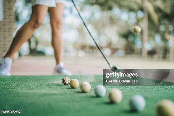 low section asian chinese female golfer practicing golf swing at driving range - golf ball in air stock pictures, royalty-free photos & images