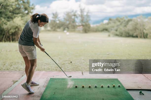 asian chinese female golfer practicing golf swing at driving range - drivingrange stockfoto's en -beelden