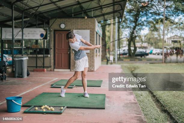 asian chinese female golfer practicing golf swing at driving range - driving range stock pictures, royalty-free photos & images