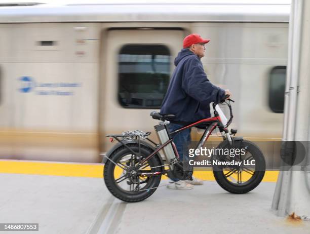 Commuter stands on the platform of the LIRR station in Hicksville, New York, with an electric bicycle on April 27, 2023.