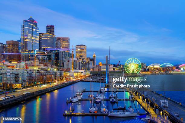 colorful shot of the seattle waterfront with pier, restaurant and business skyscraper building during twilight time in washington, usa. - seattle fotografías e imágenes de stock