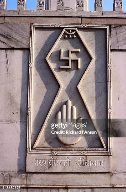 the swastika and open palm carved on the walls of the digambara jain temple. the swastika symbol is second only to the om in hindu divinity. the word swastika means auspicious in the sanskrit language. - digambara stock-fotos und bilder