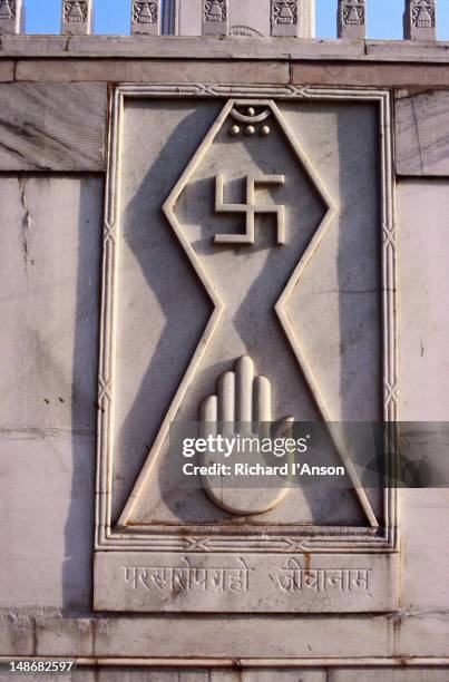 the swastika and open palm carved on the walls of the digambara jain temple. the swastika symbol is second only to the om in hindu divinity. the word swastika means auspicious in the sanskrit language. - digambara stockfoto's en -beelden