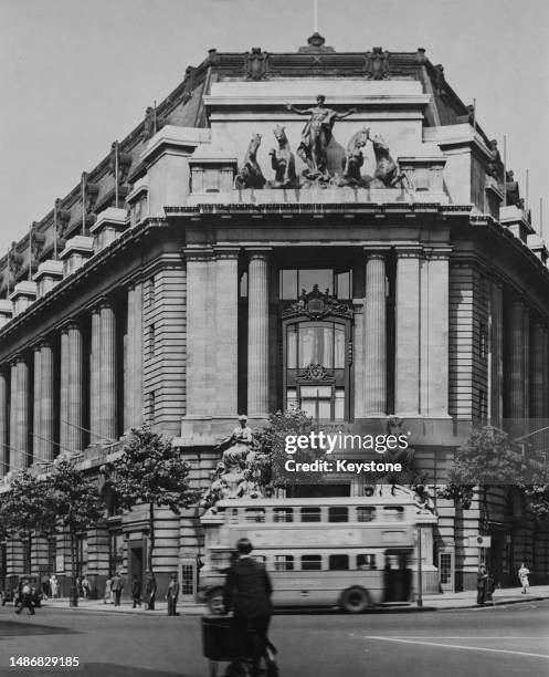 Pedestrians and a double-decker bus pass the entrance of Australia House on the Strand in London, England, circa 1935. Designed by British...