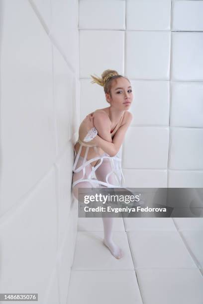 portrait of a girl in a bodysuit near the soft wall of a psychiatric ward - magazine mockup stock pictures, royalty-free photos & images